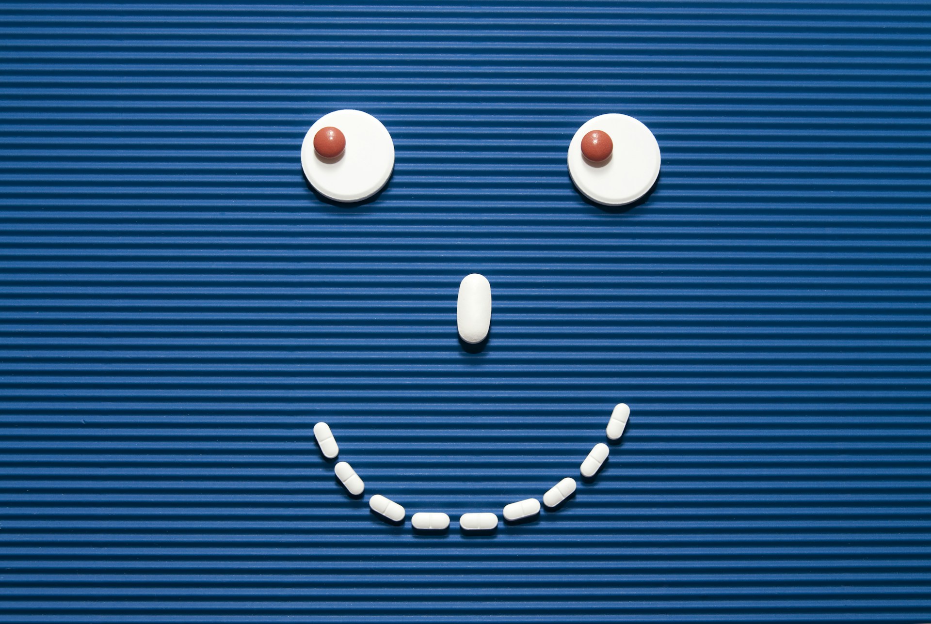 A smiley face made out of pills on a blue background