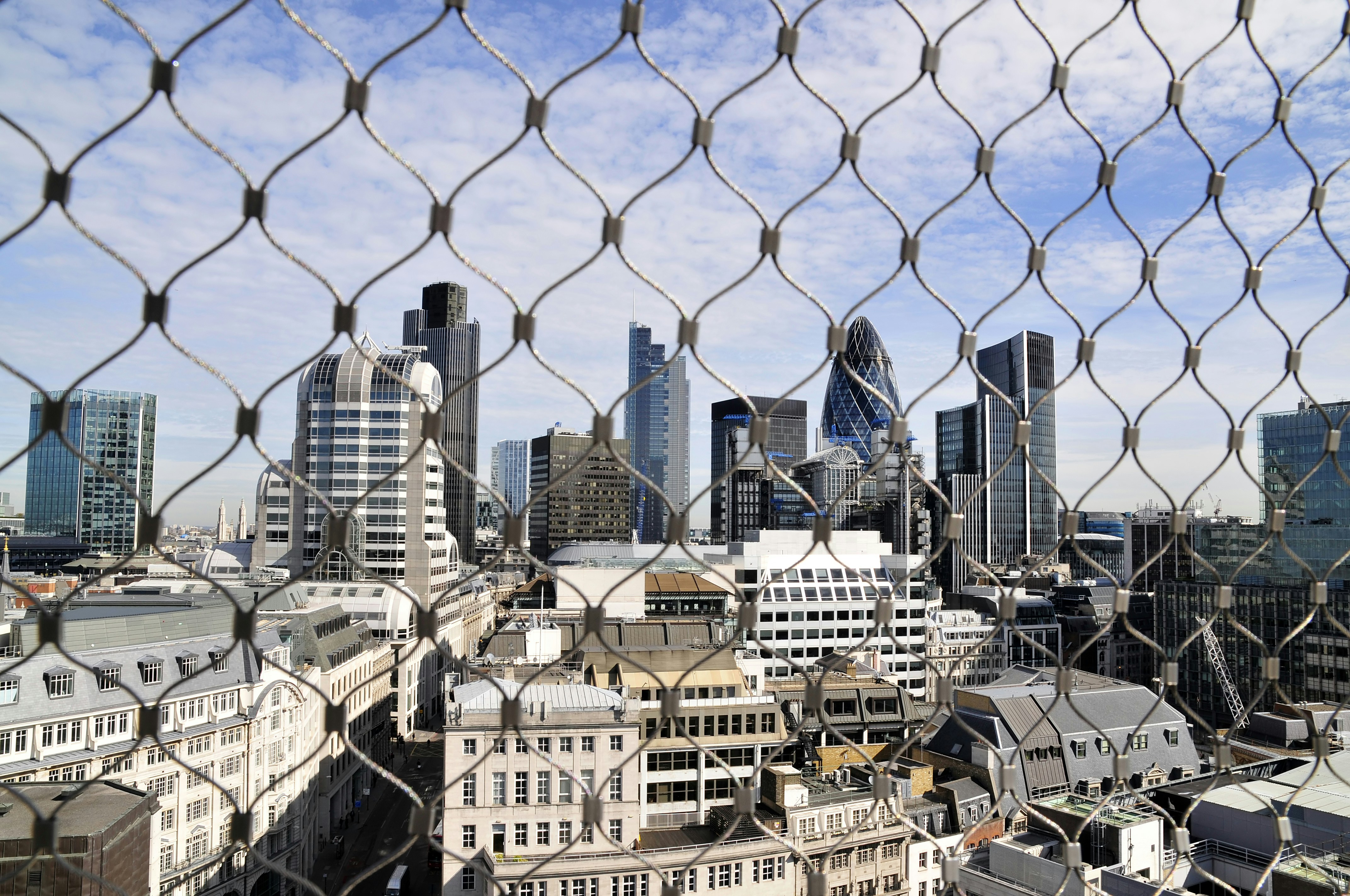 A view of a city through a chain link fence