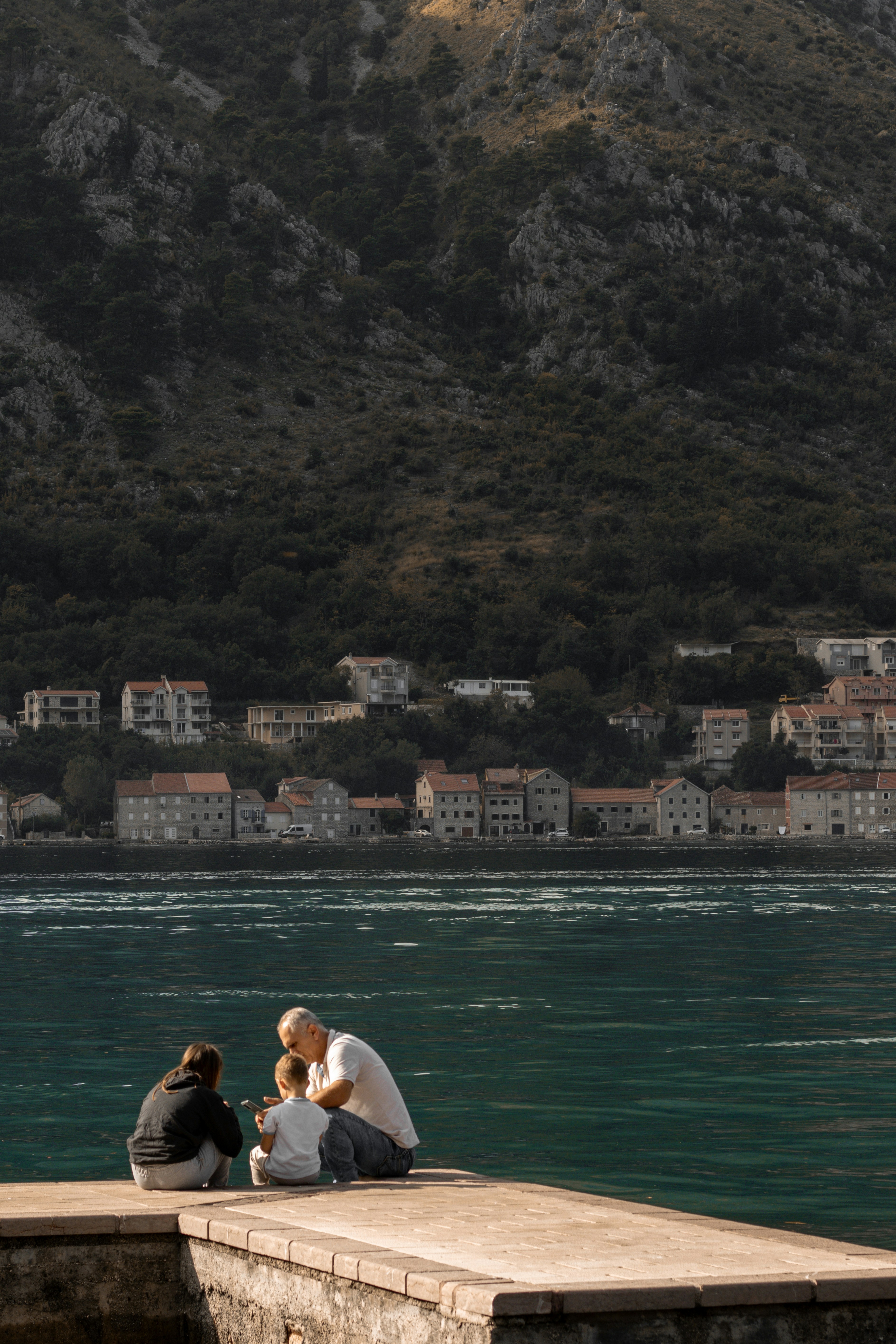 A couple of people sitting on top of a pier next to a body of water