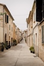 A narrow street lined with stone buildings and green shutters
