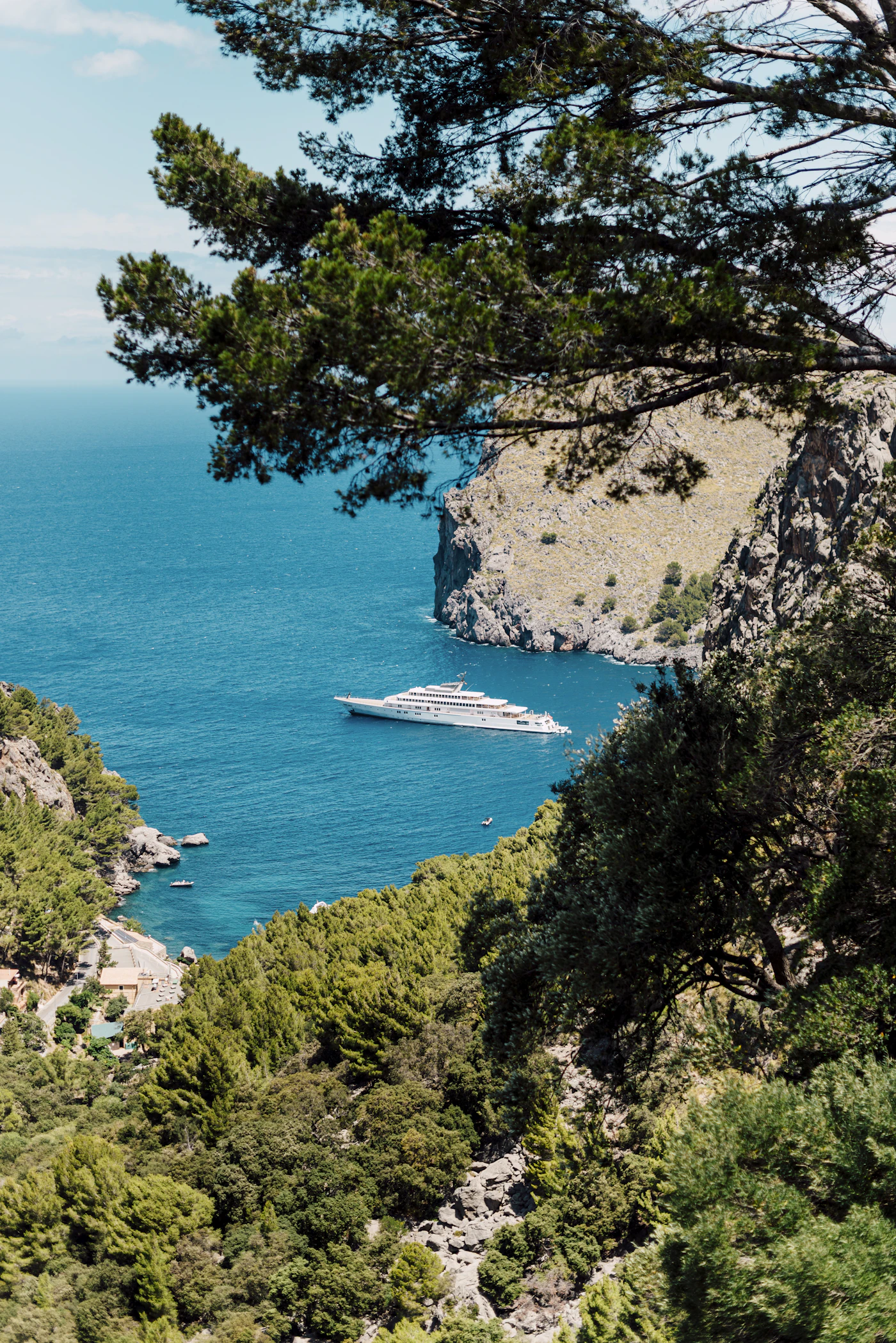 Un petit bateau traversant l'eau bleue profonde au pied des falaises calcaires de la côte nord-ouest de Majorque, à Sa Calobra.