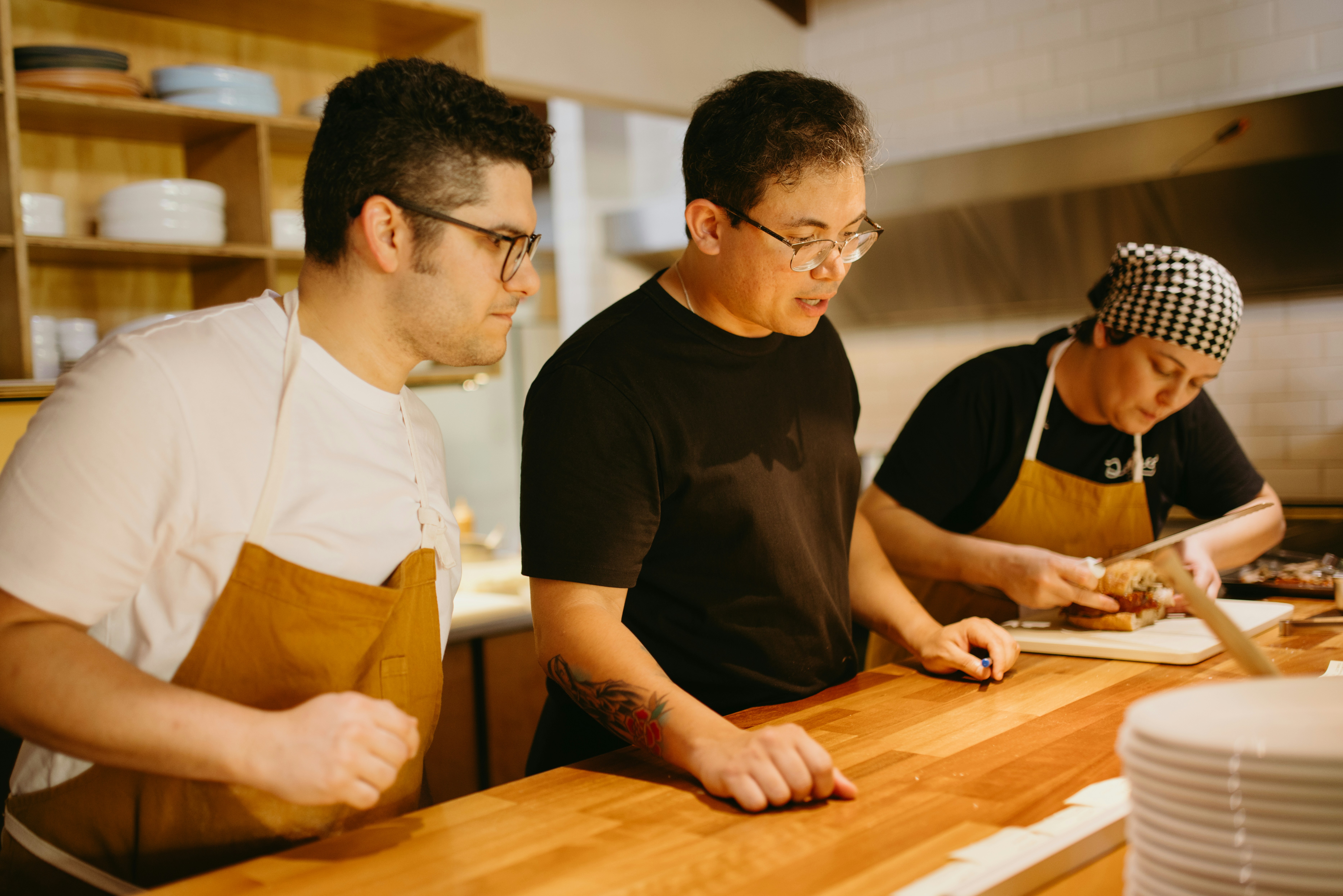 Kitchen team training at a prep station with a chef demonstrating techniques.