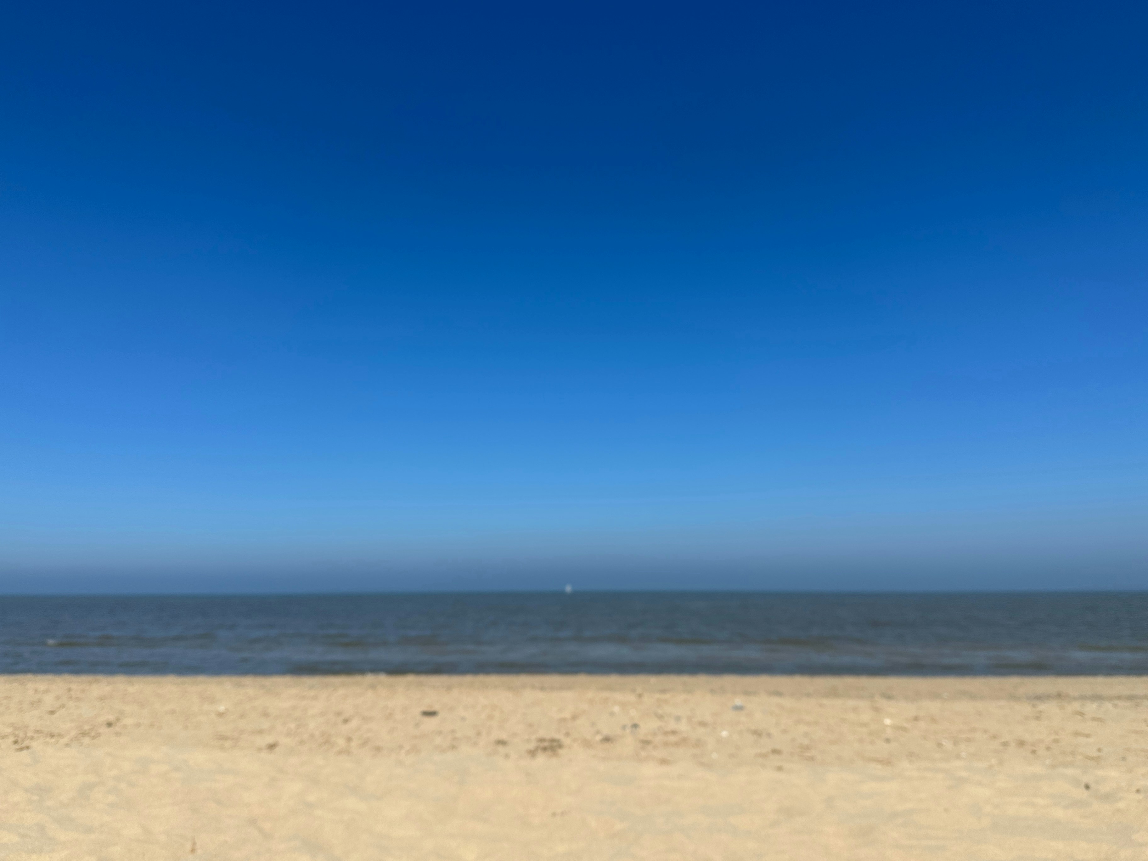 A blurry photo of a beach with a blue sky