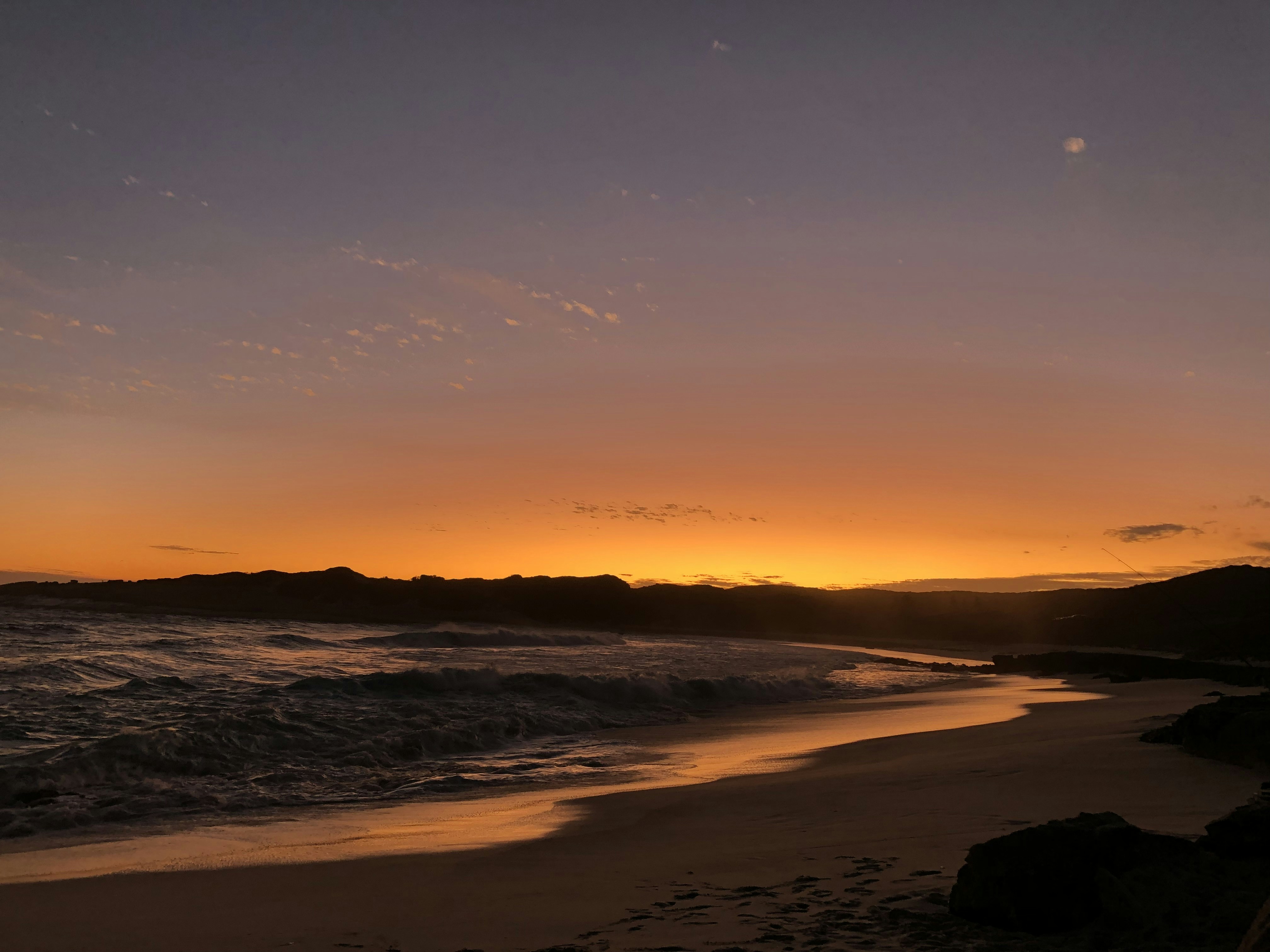 The sun is setting over the ocean on the beach