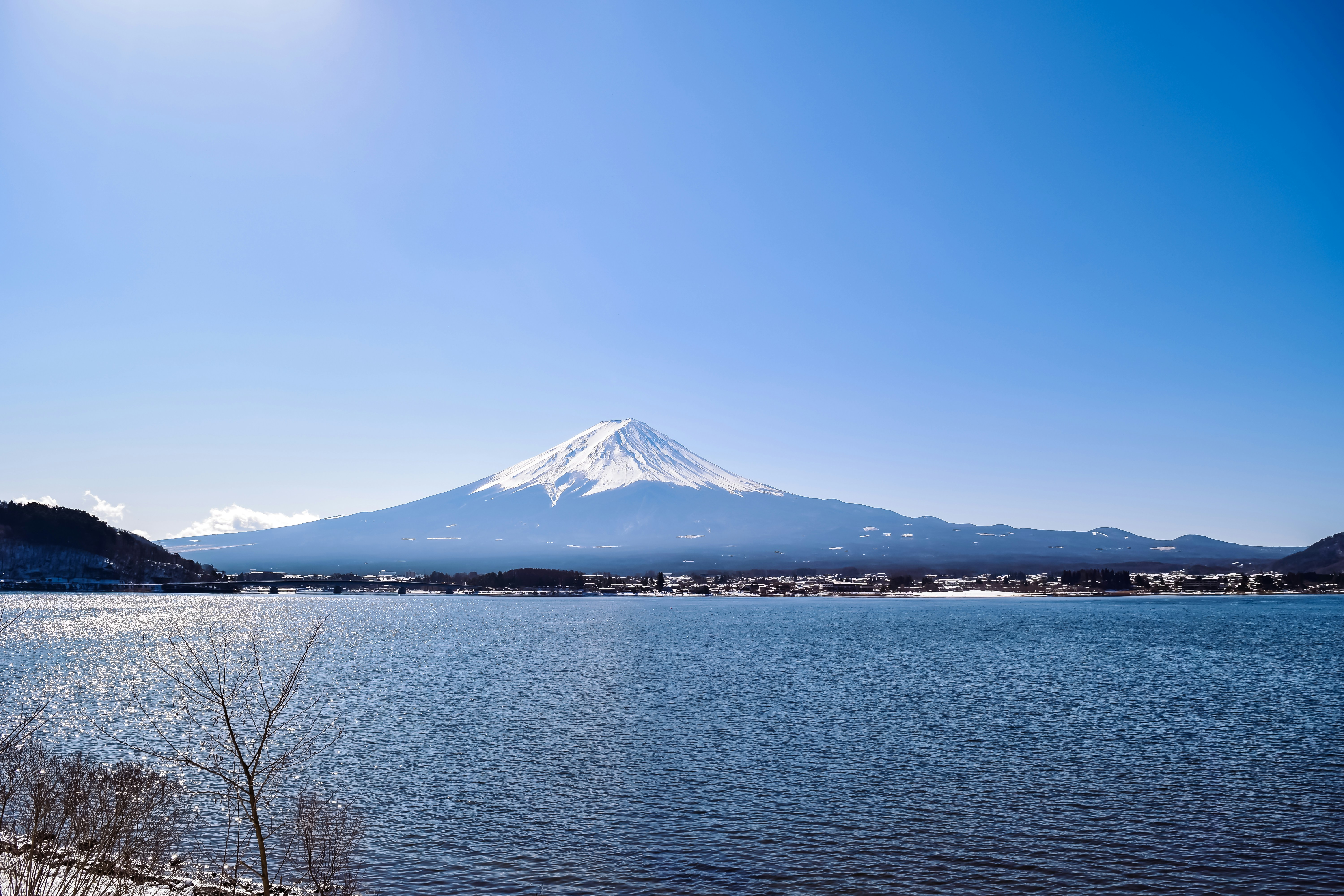 A lake surrounded by snow covered mountains under a blue sky