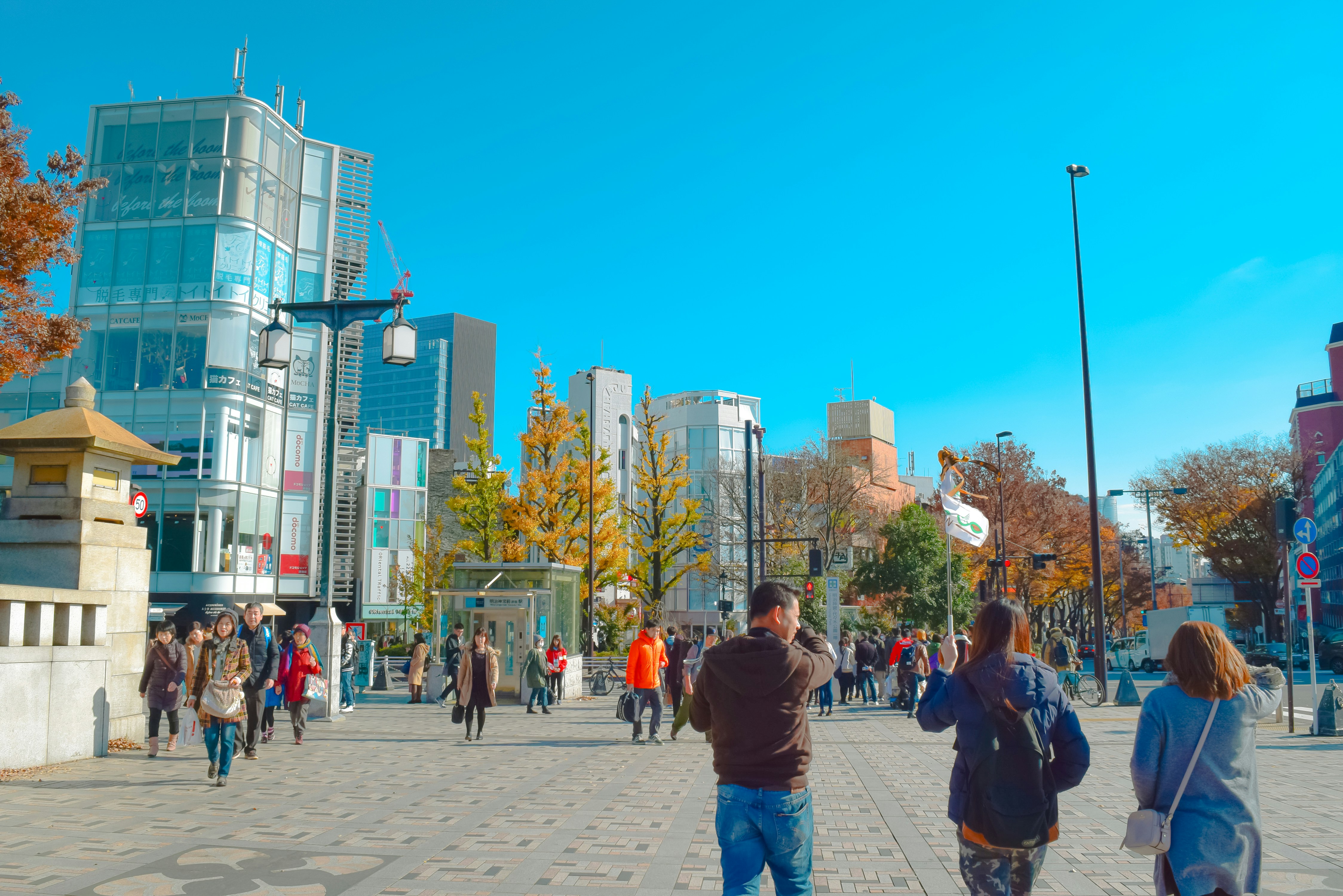 A group of people walking down a street next to tall buildings
