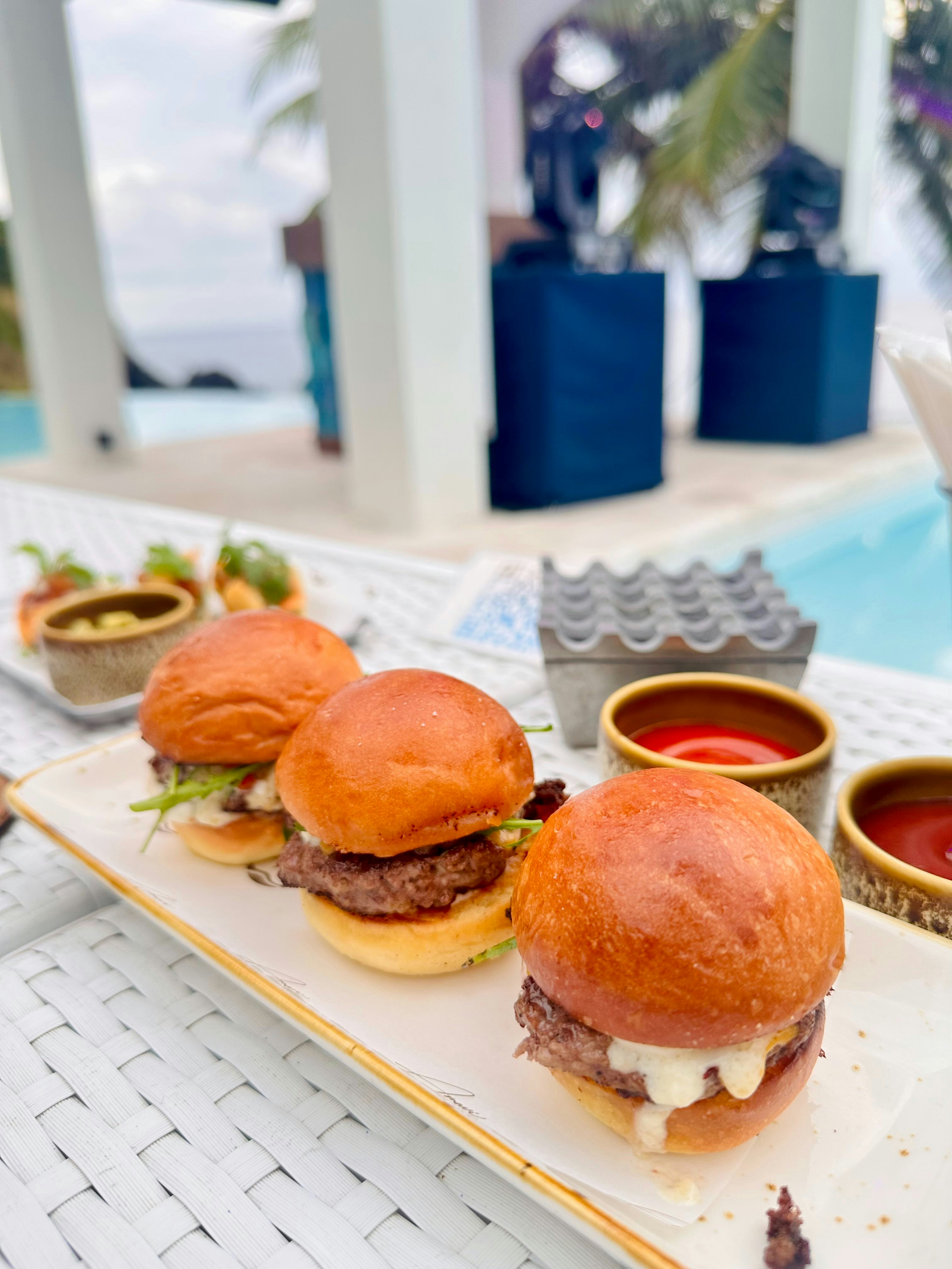 A row of hamburgers sitting on top of a white plate next to a pool