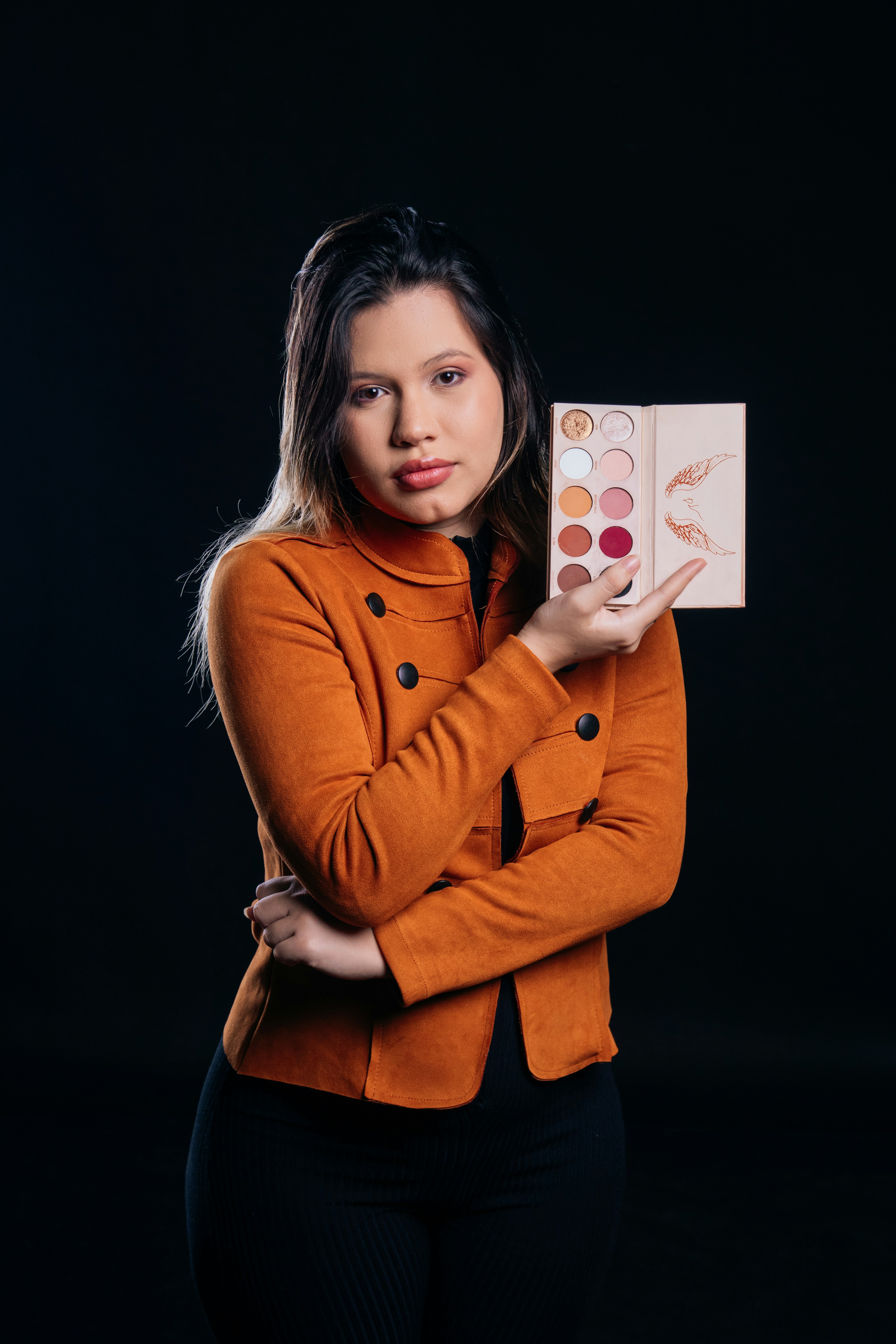 A woman holding up a palette of makeup