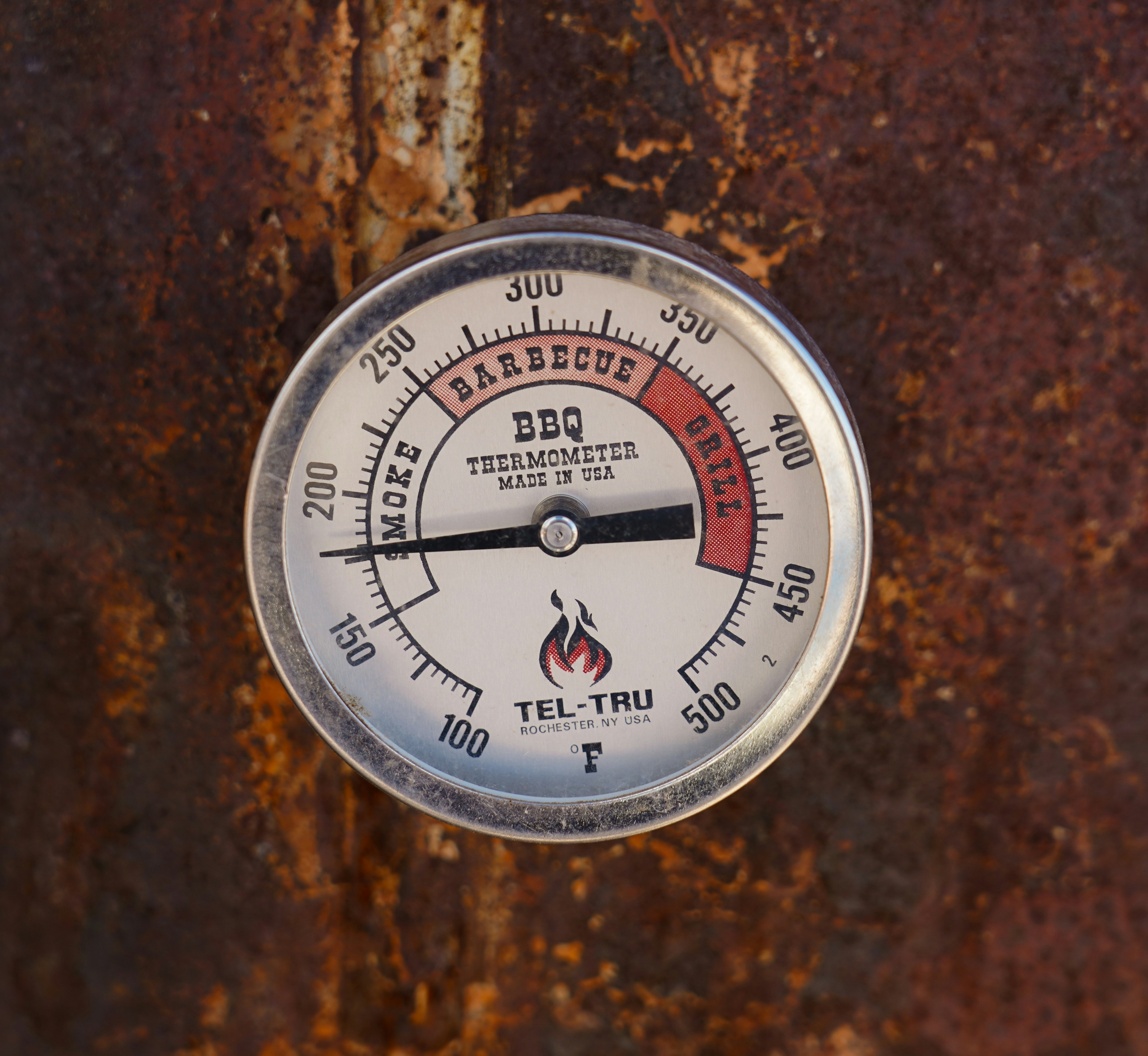 A close up of a thermometer on a rusted surface