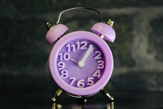 A pink alarm clock sitting on top of a table