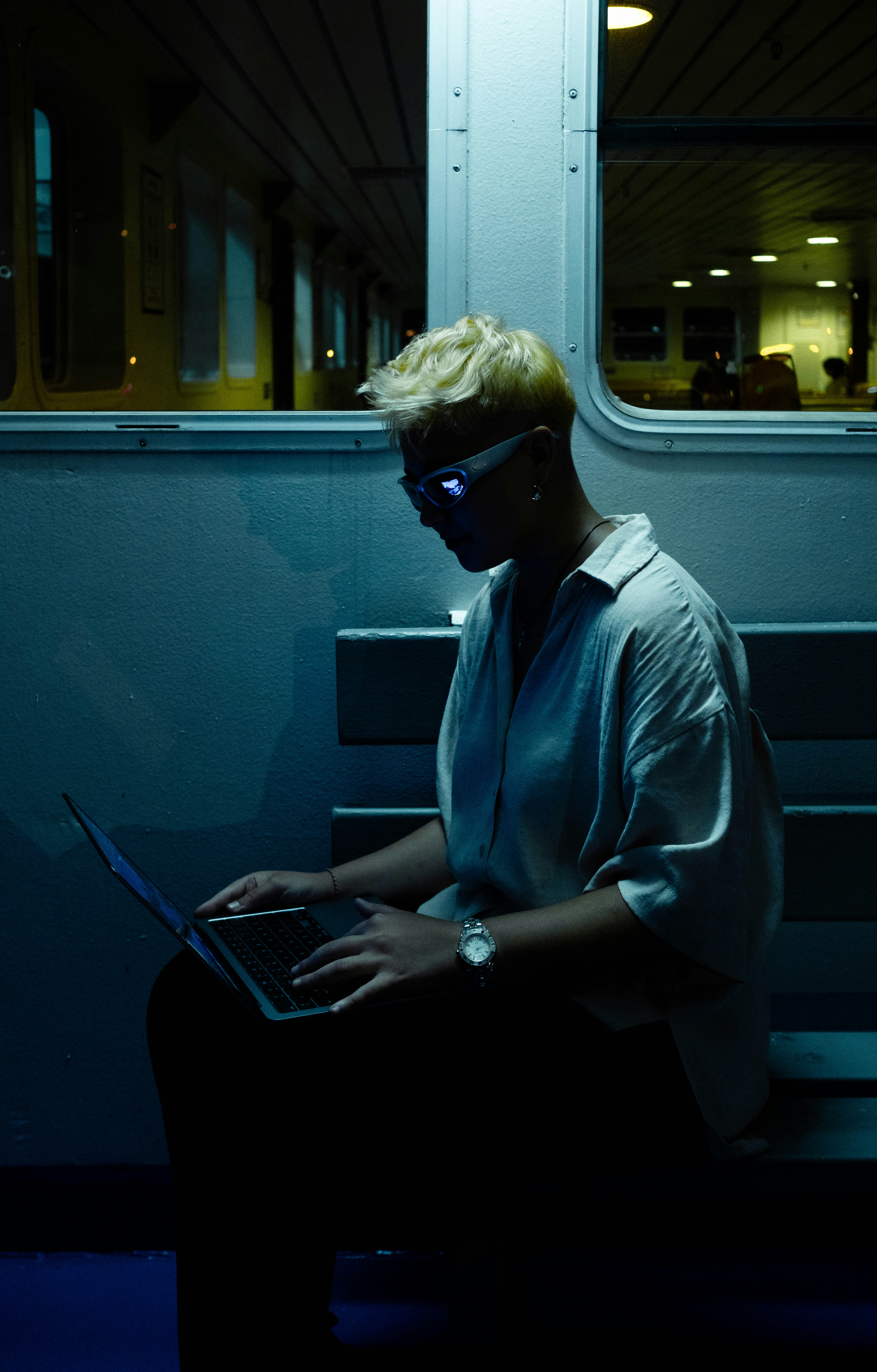 A man sitting on a train using a laptop computer