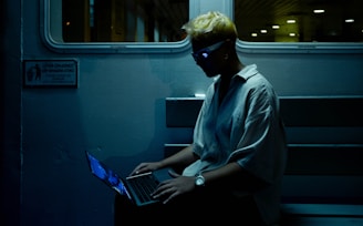 A man sitting on a train using a laptop computer