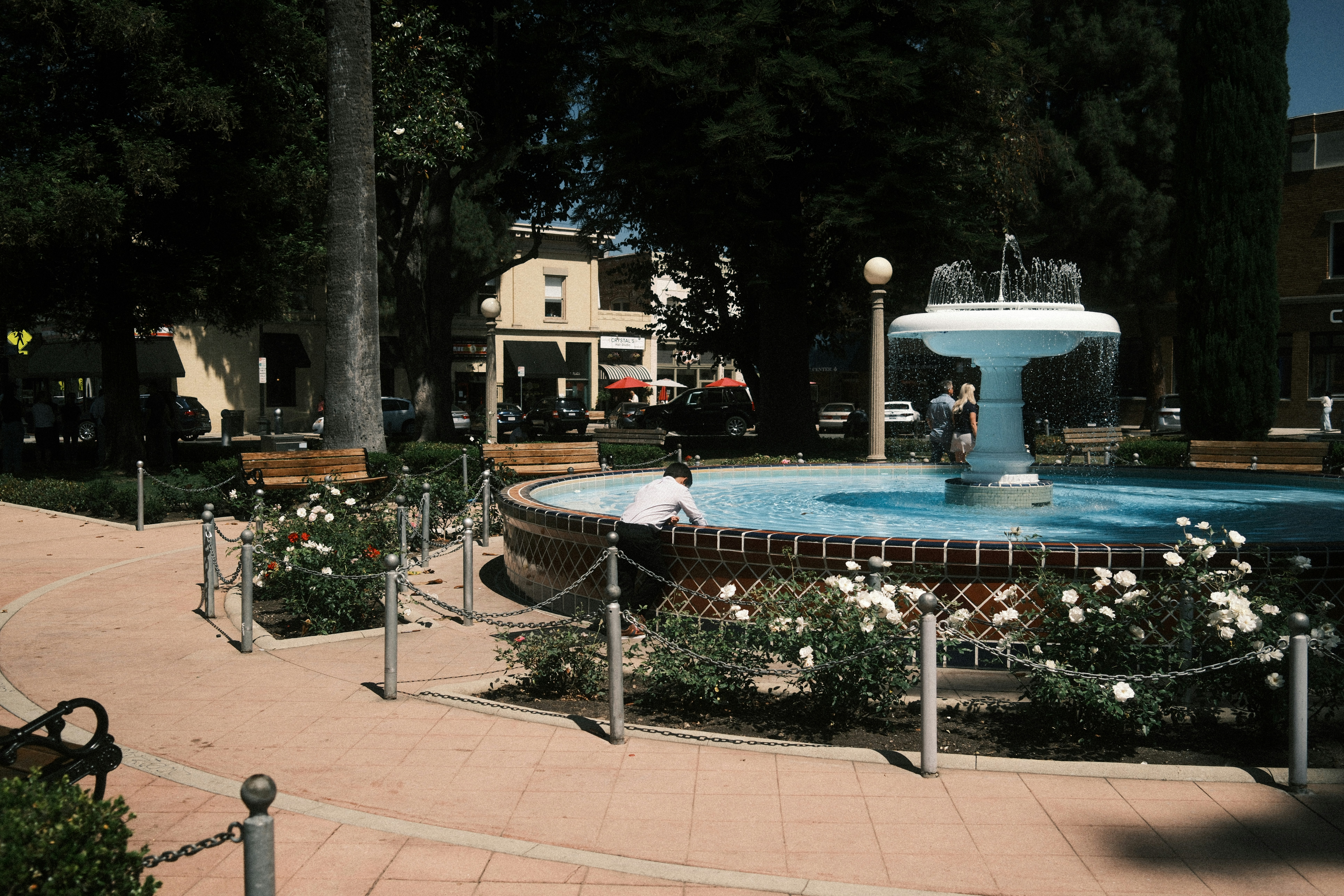 A fountain in a park with flowers around it