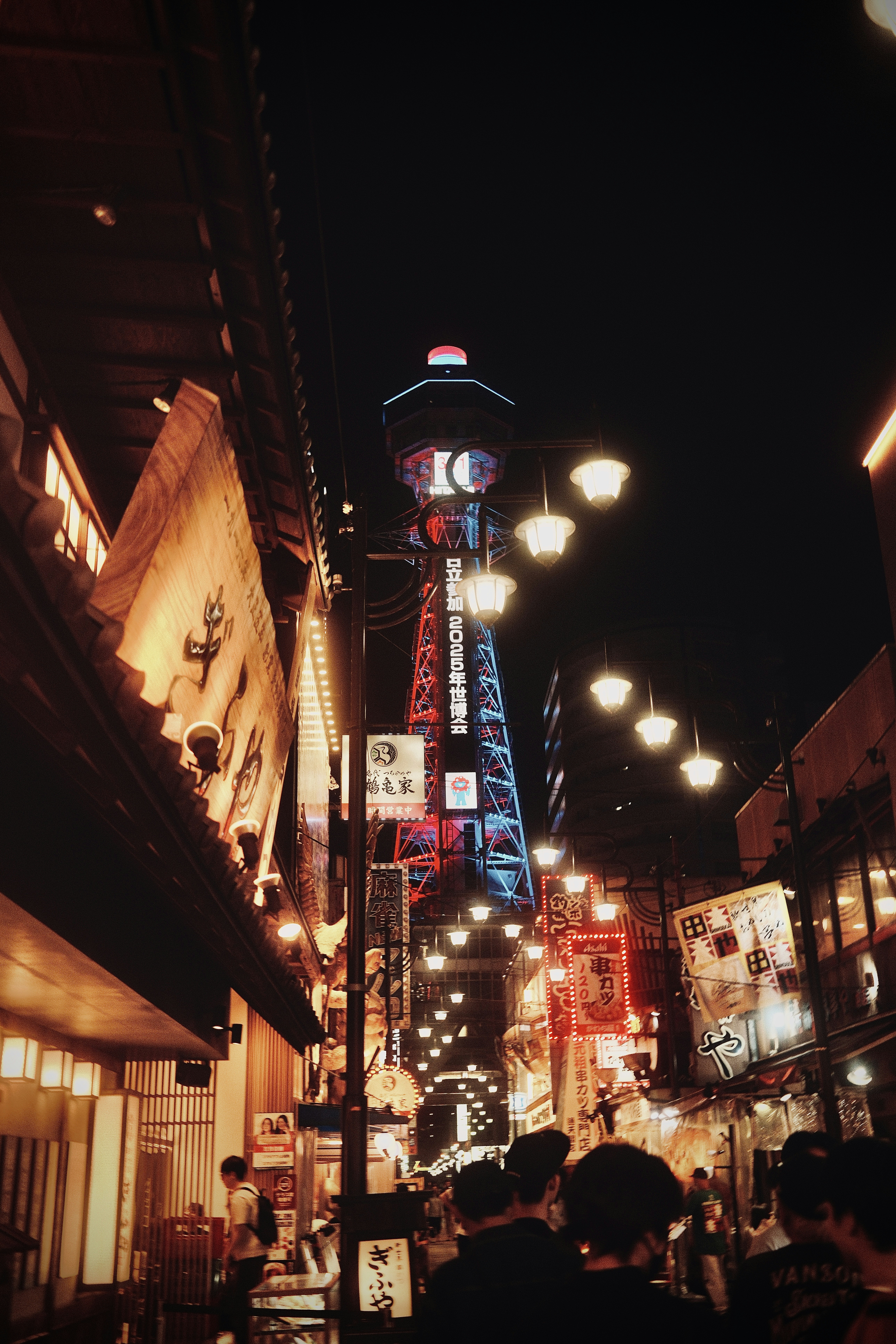 A crowded city street at night with a tower in the background