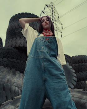 A woman in overalls standing in front of a rock formation