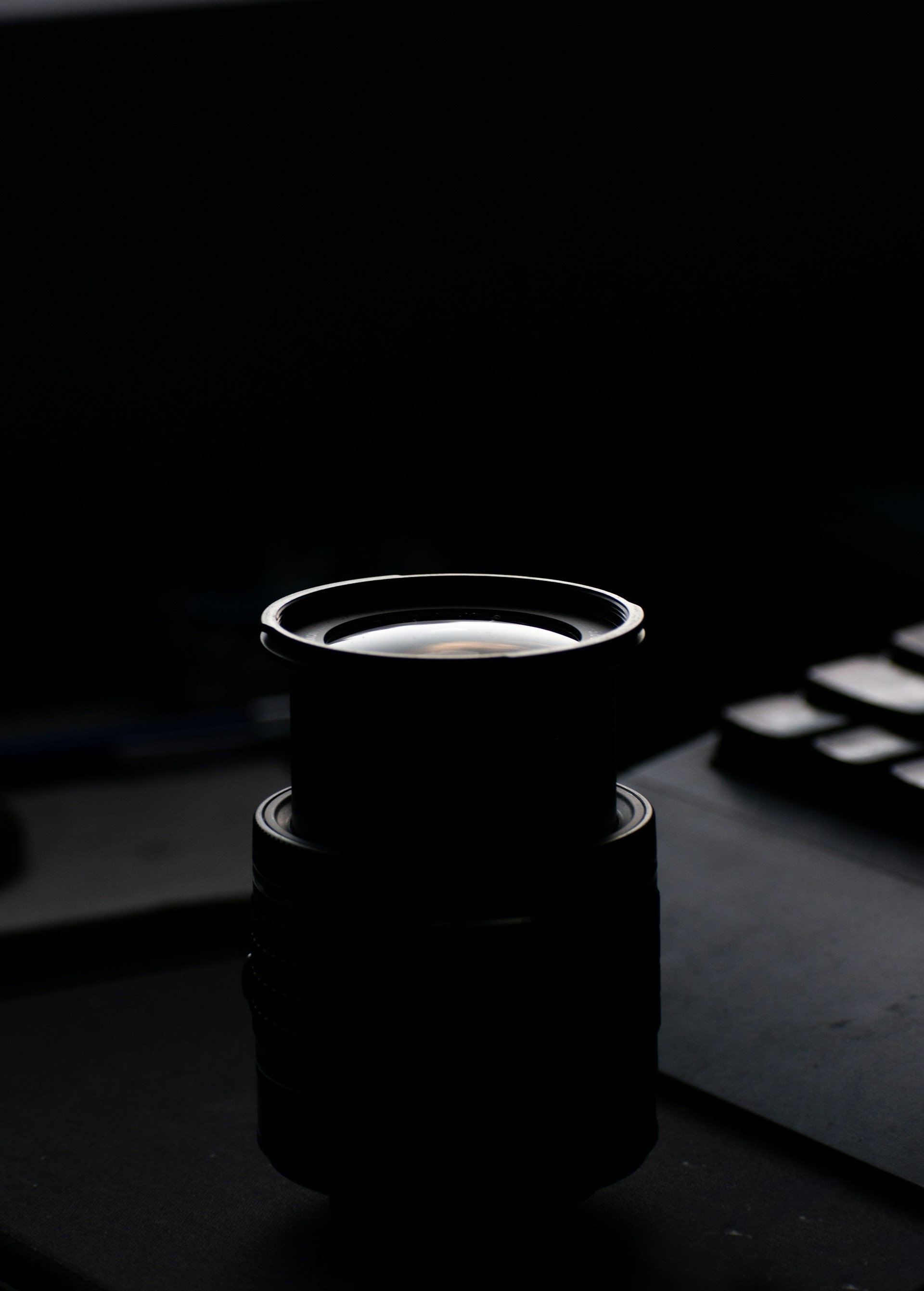 A black cup sitting on top of a desk next to a keyboard