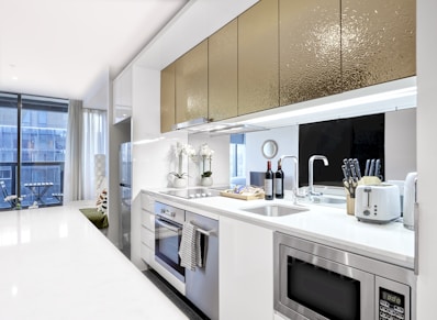 A kitchen with a stove, sink, microwave and a window