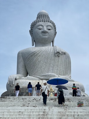 A group of people standing around a large buddha statue