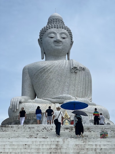 A group of people standing around a large buddha statue