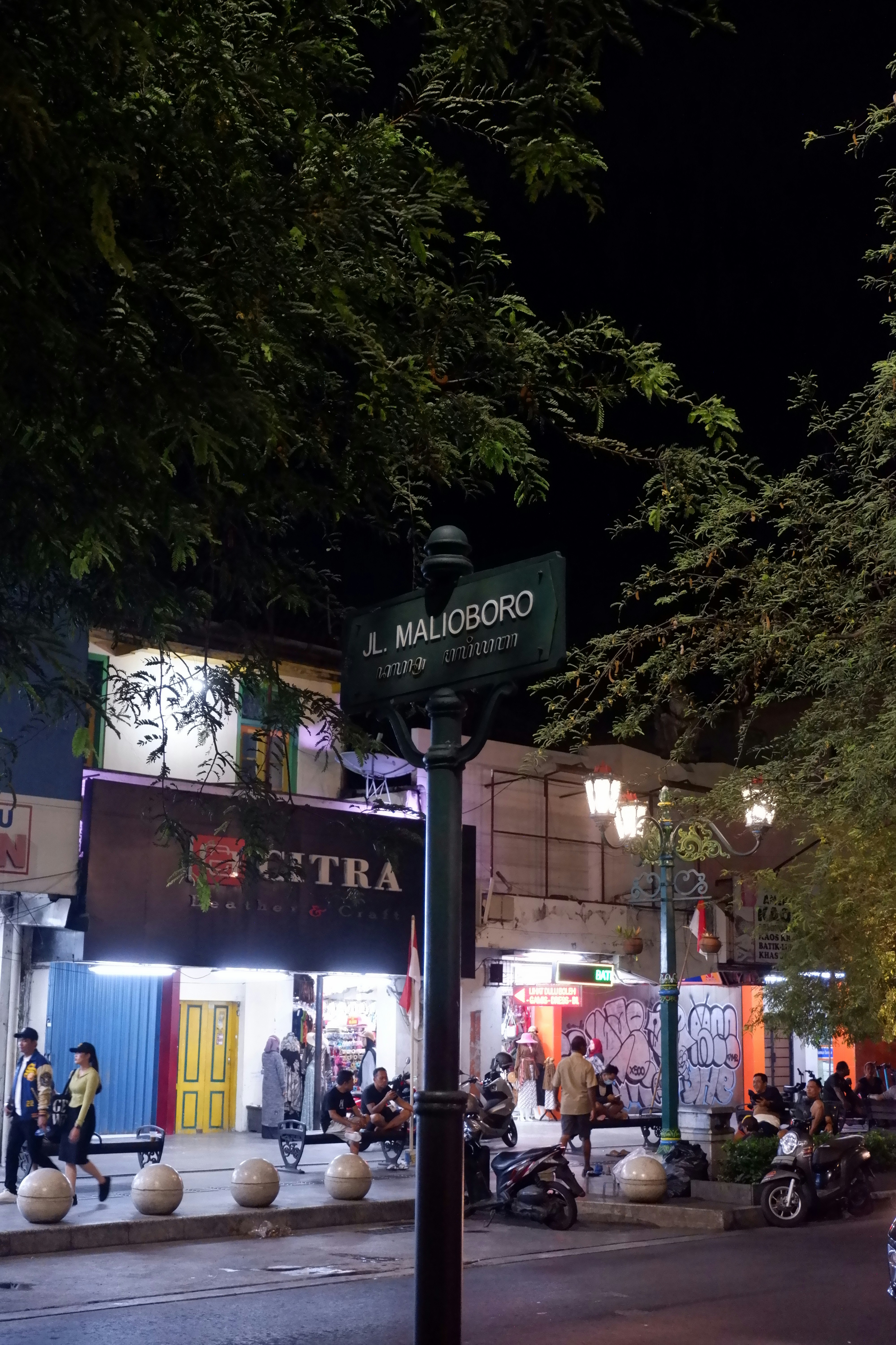 A city street at night with people walking on the sidewalk