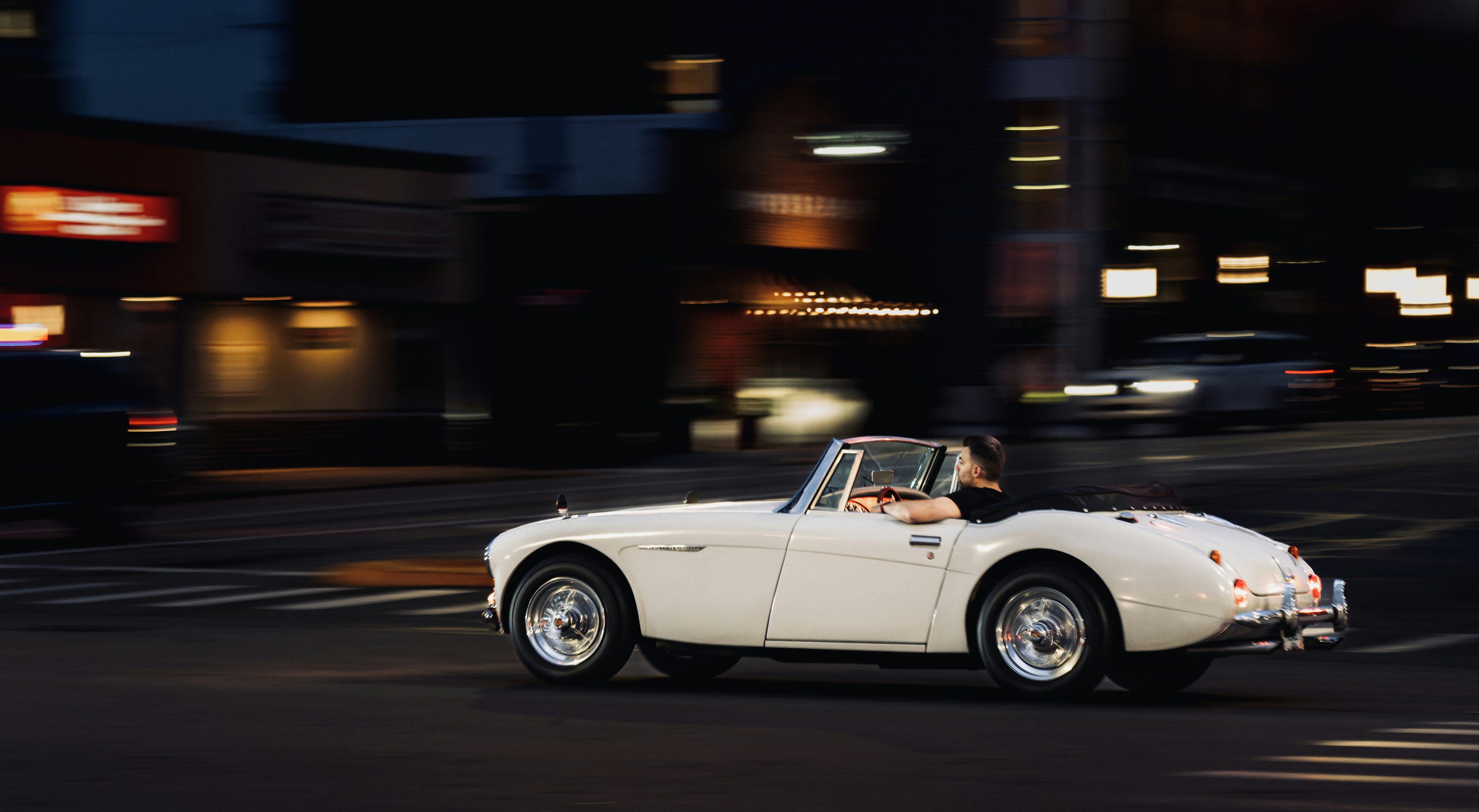 A white sports car driving down a city street photo – Free Wallpaper ...