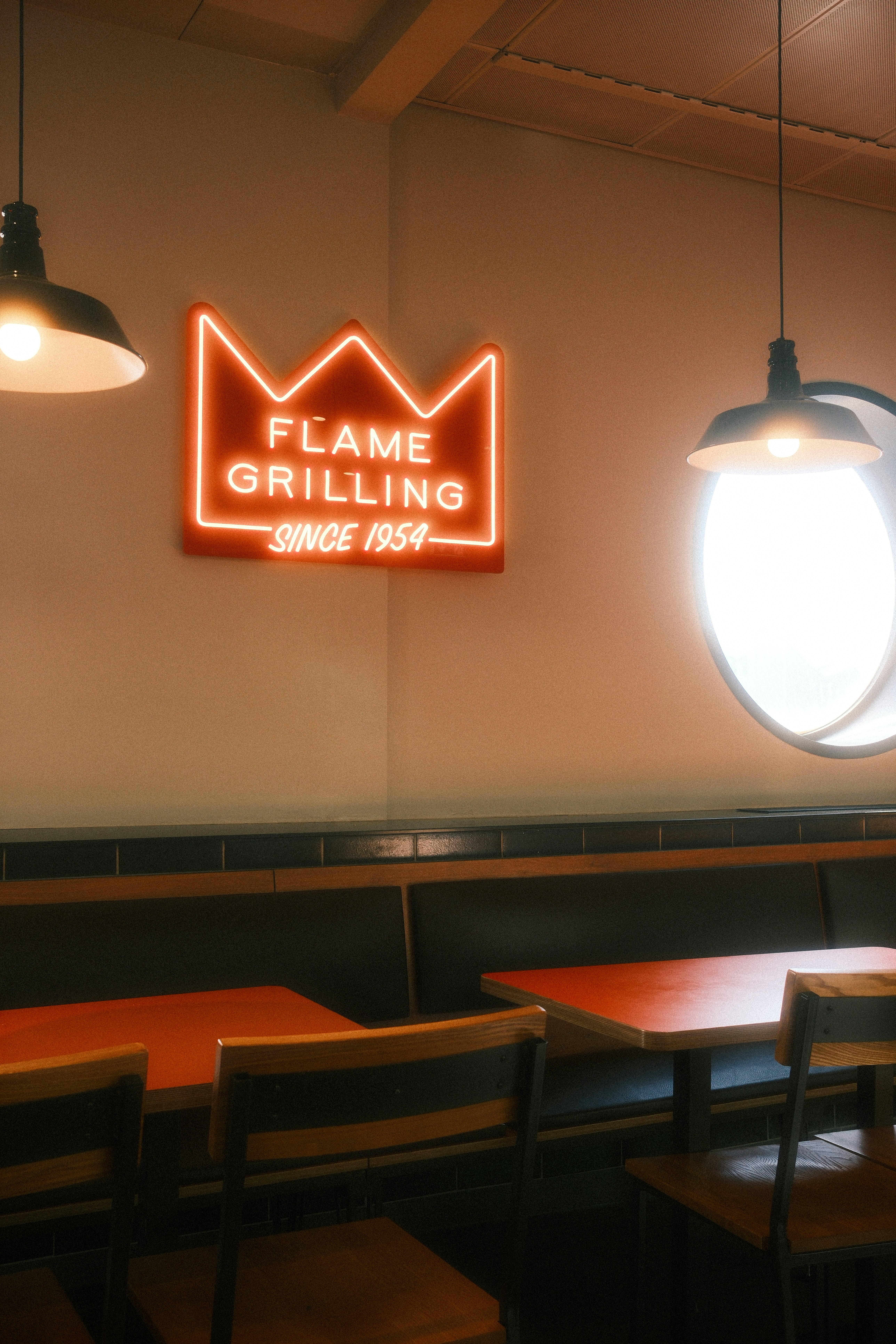 A restaurant with wooden tables and chairs and a neon sign on the wall