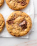 Four chocolate chip cookies on a piece of parchment paper