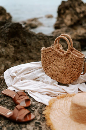 A straw hat, sandals and a straw bag on a rock