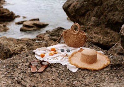 A hat, a bag, and other items are on the ground near the water