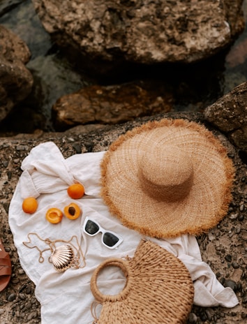 A hat, a bag, and other items are laying on a rock