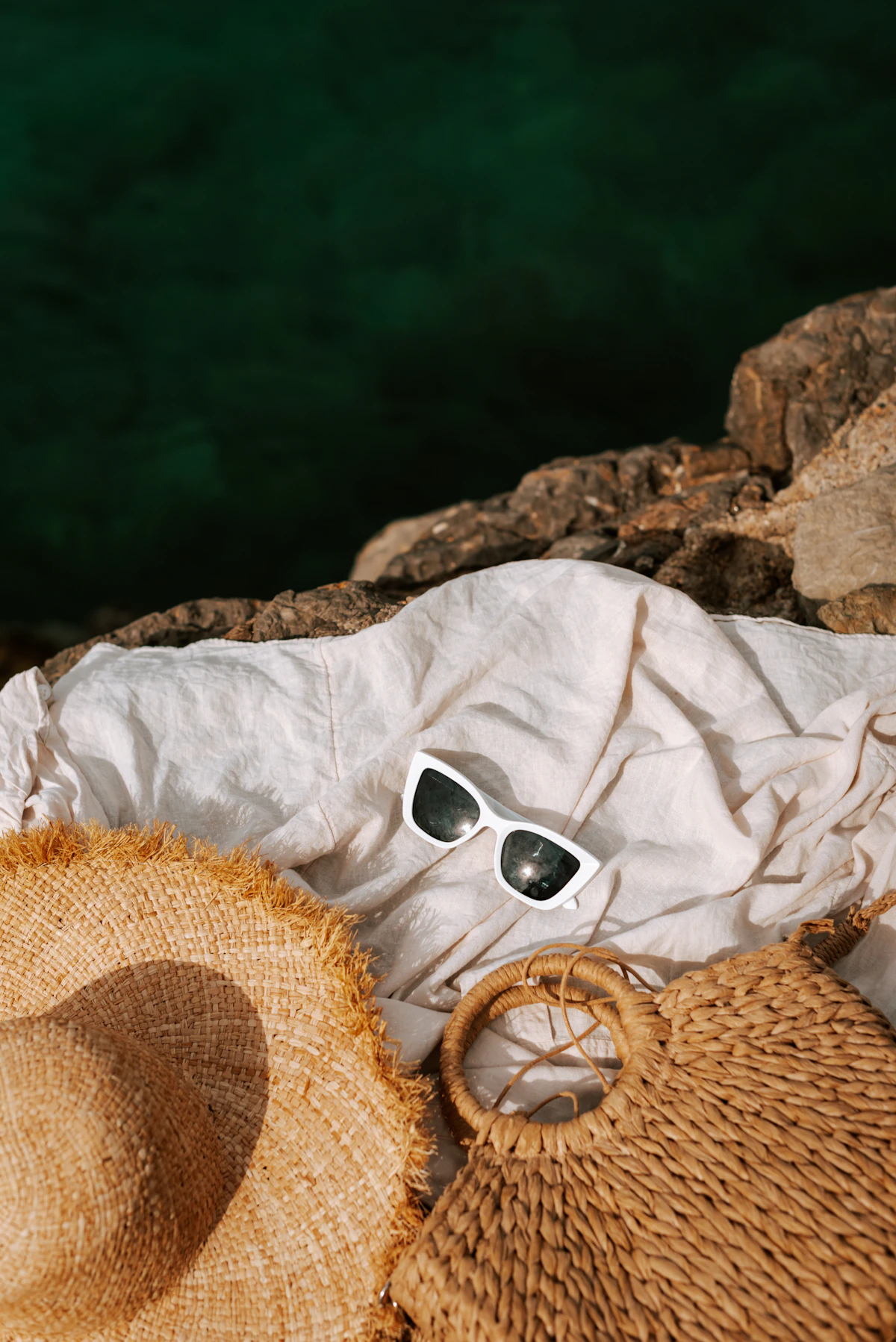 Hat, sunglasses, and woven accessories styled by the coast