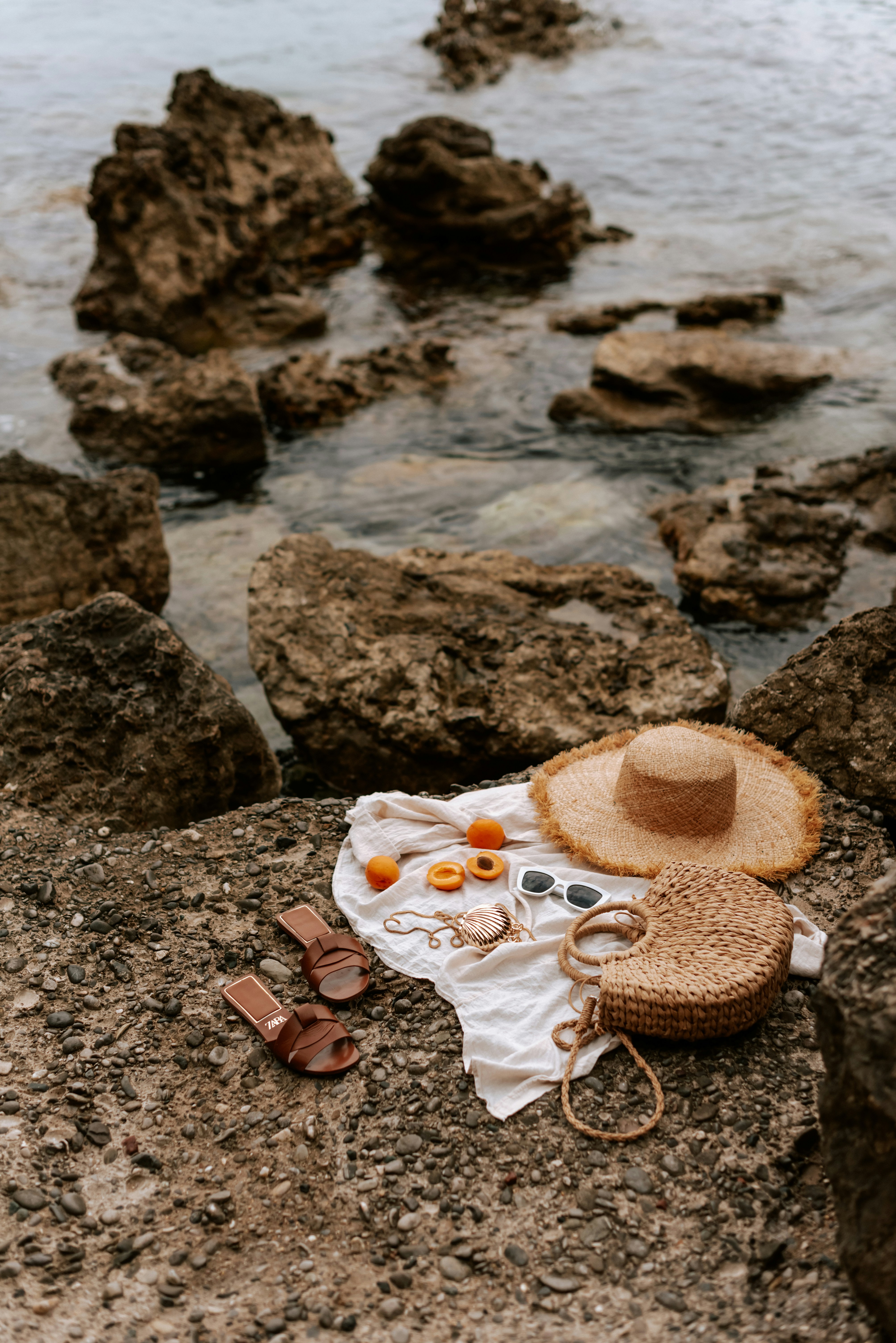 A hat, a towel, and other items on a rock near the waterby Kateryna Hliznitsova