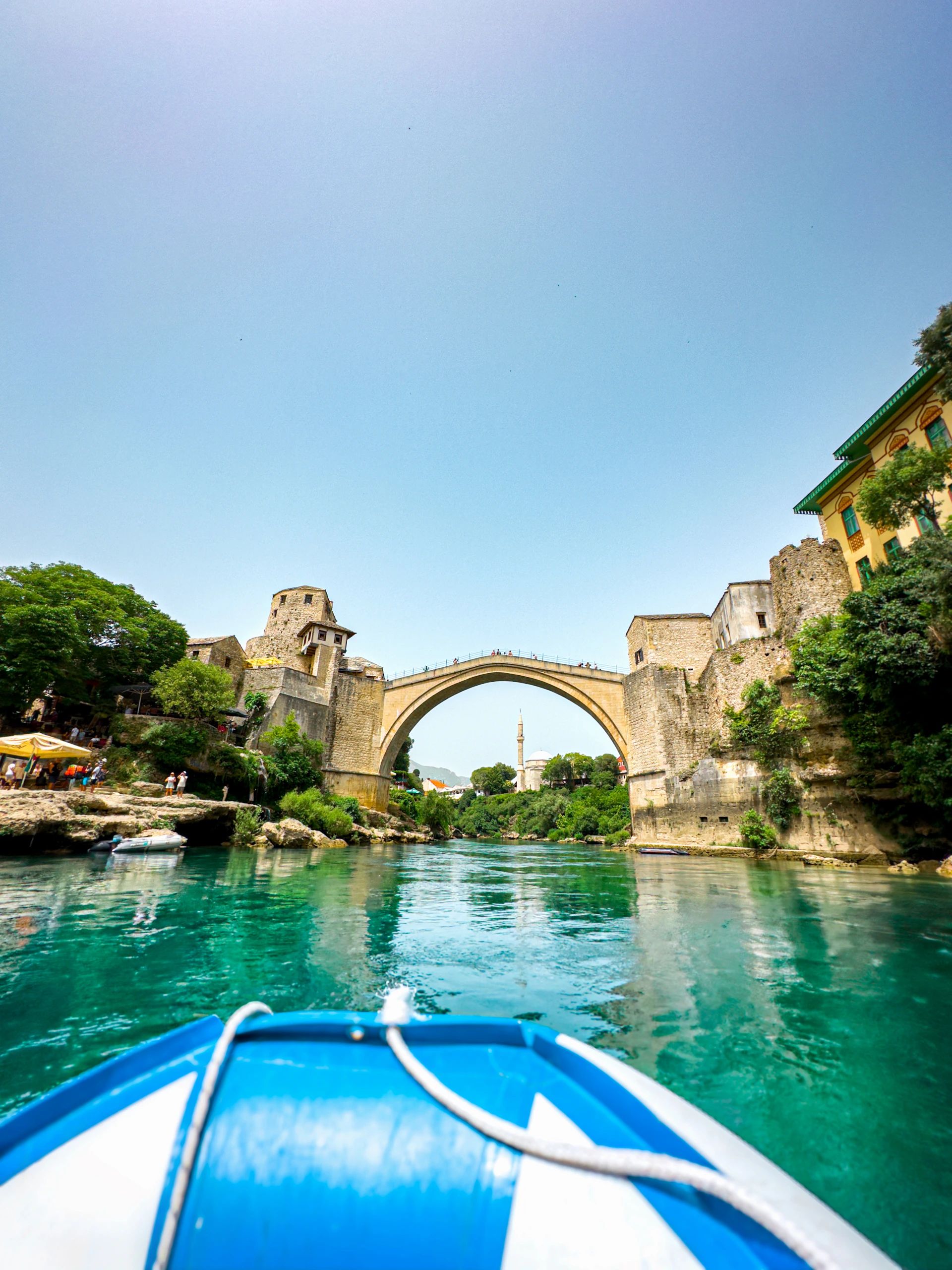 A boat traveling down a river next to a bridge