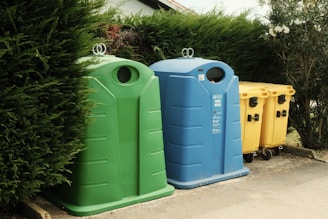 A row of trash cans sitting next to a bush