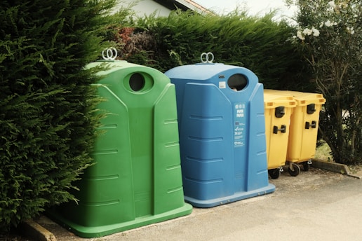 A row of trash cans sitting next to a bush
