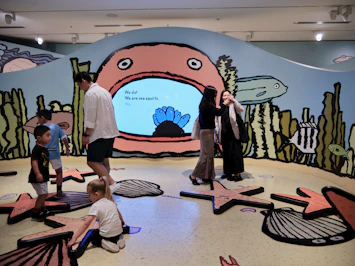 A group of people sitting on the floor in front of a mural