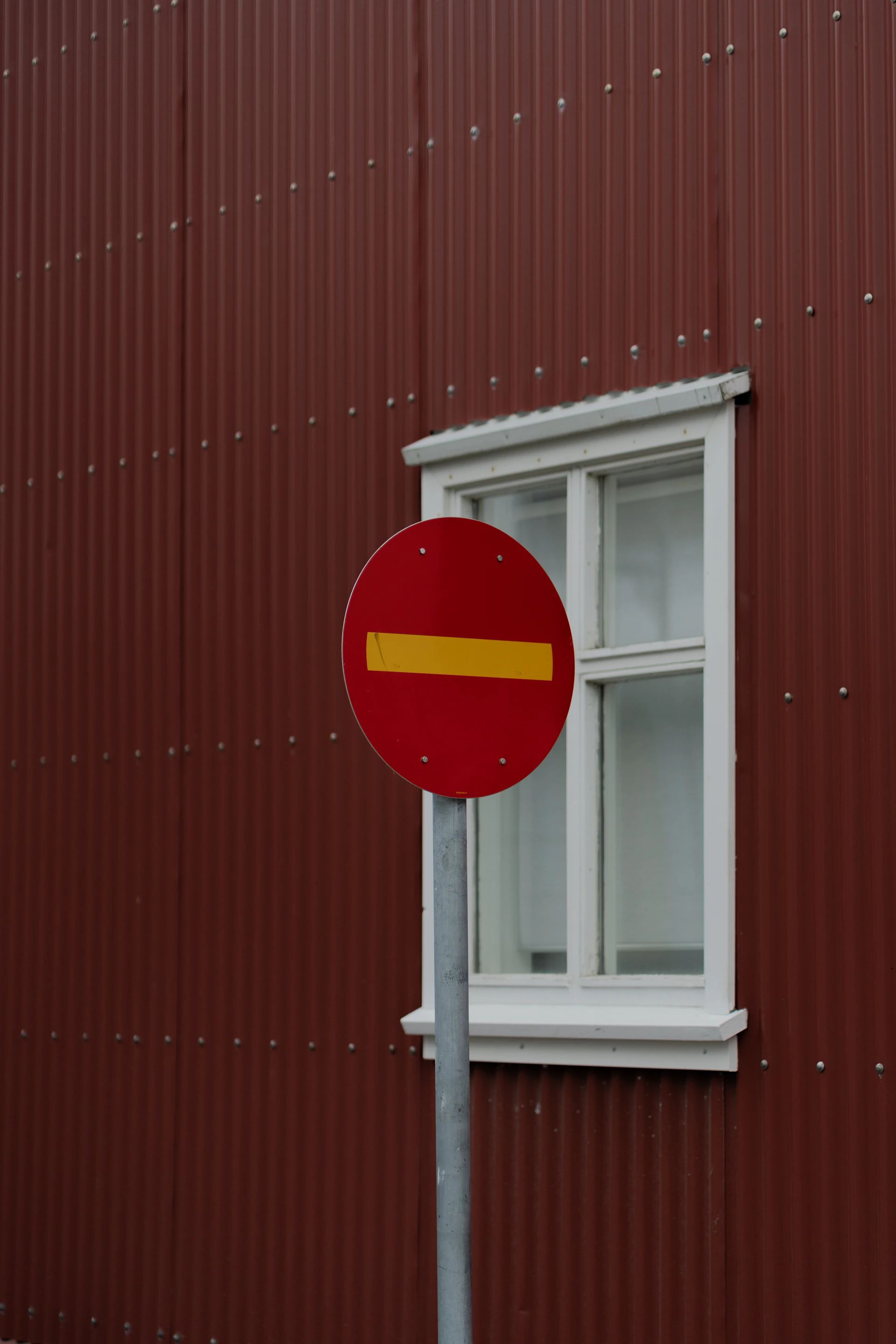 A red street sign sitting in front of a red building