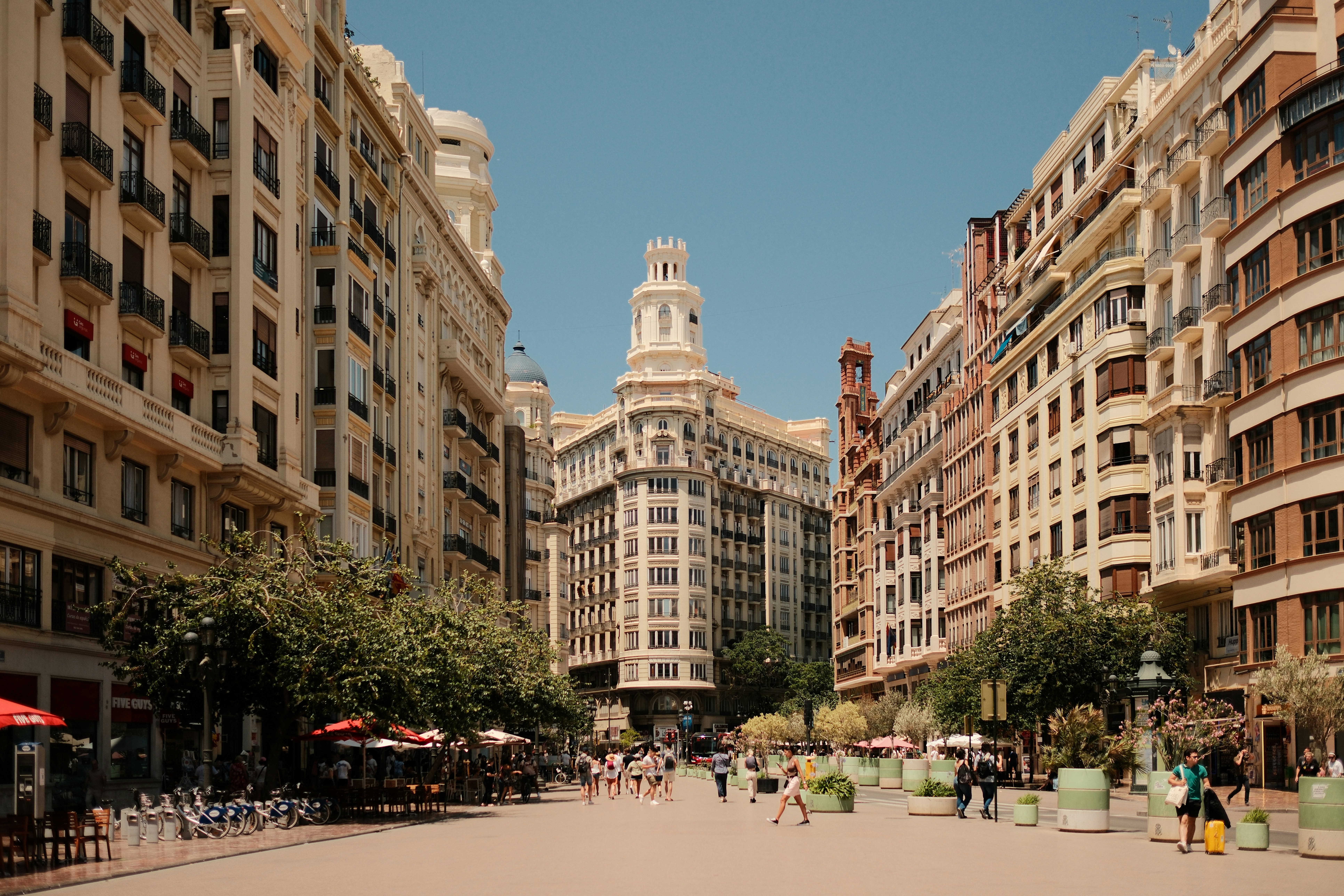 A group of people walking down a street next to tall buildings
