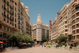 A group of people walking down a street next to tall buildings