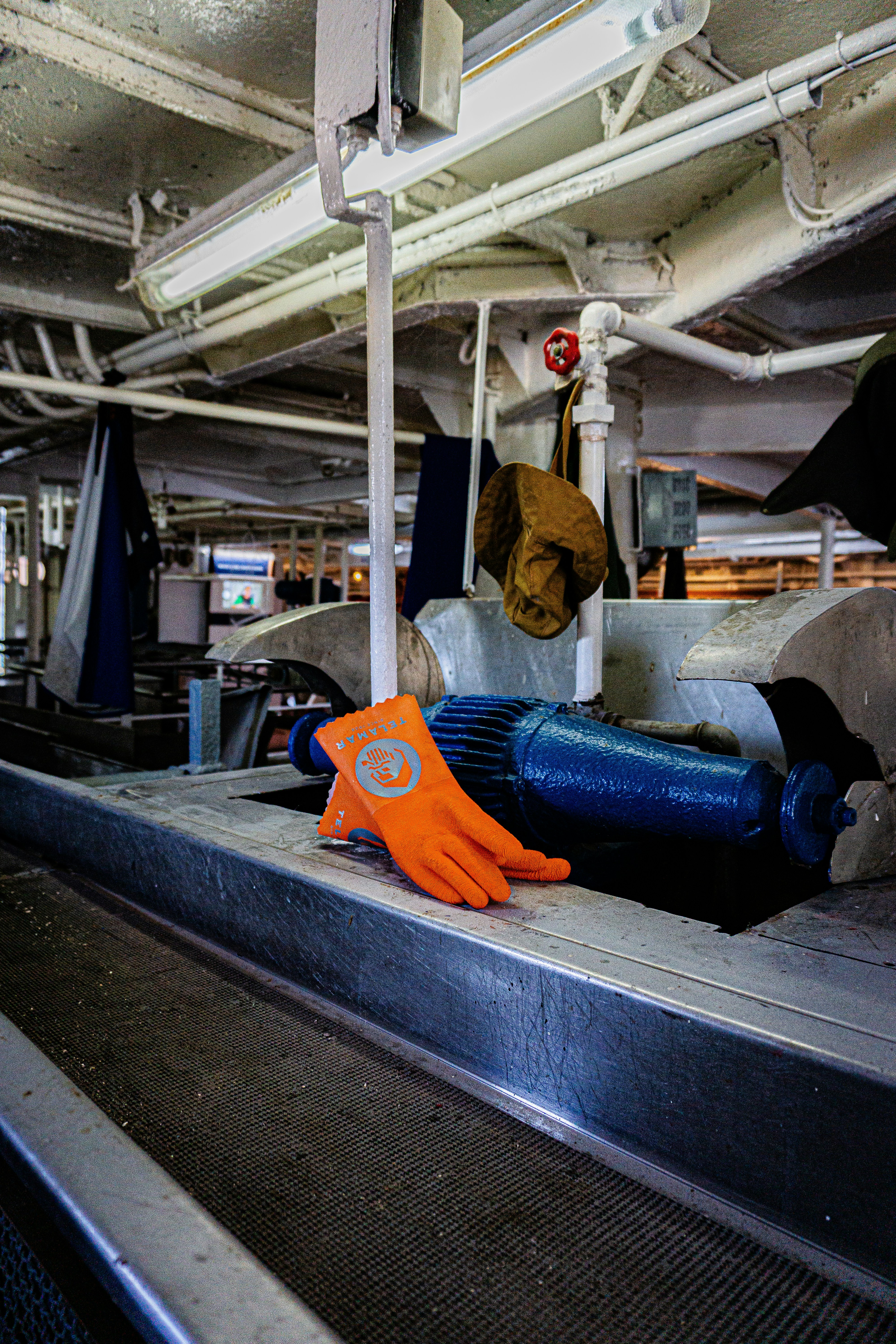 Orange work gloves on dark steel surface, bright studio lighting, well-lit