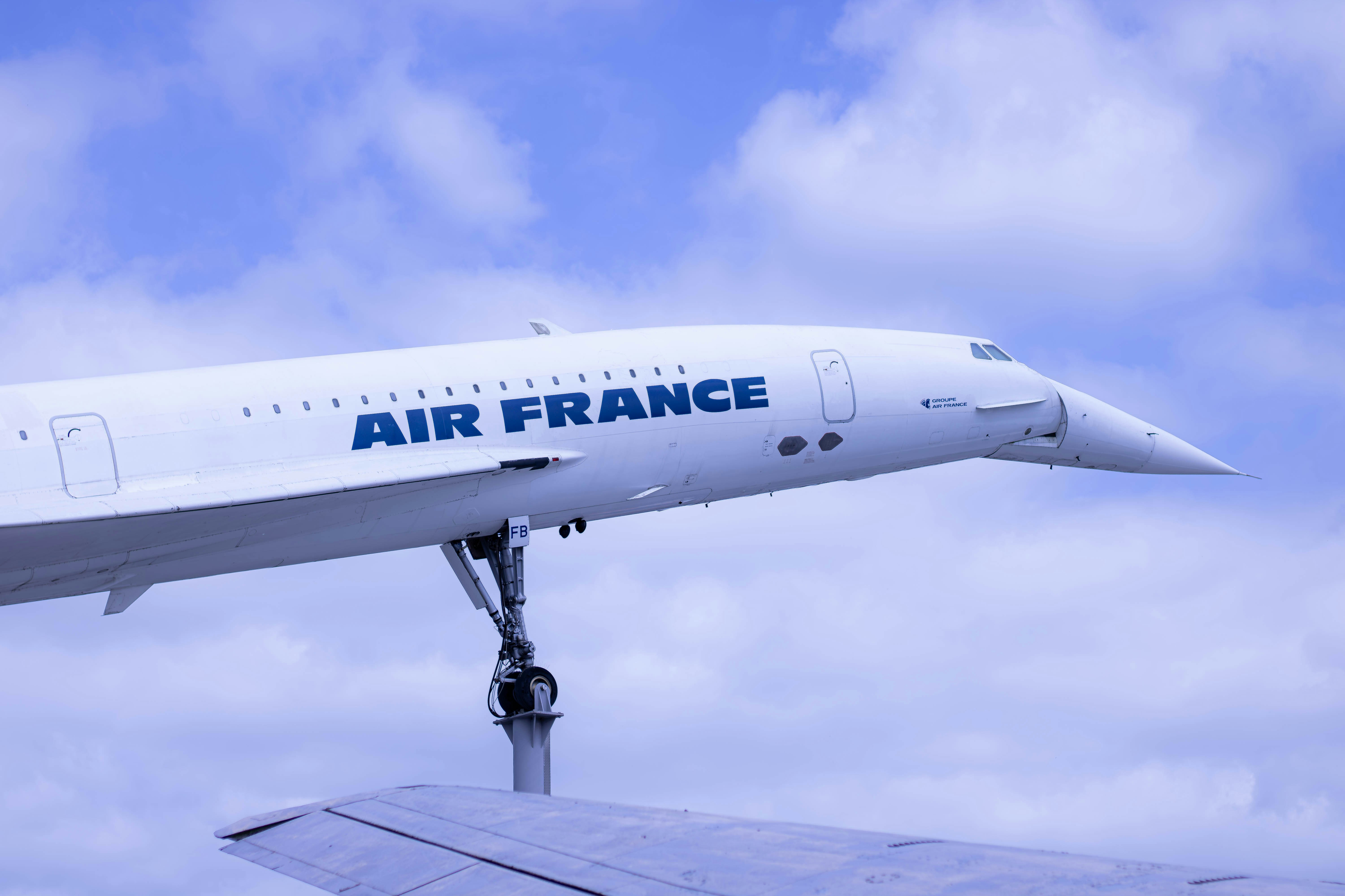 A large air france jetliner flying through a cloudy blue sky, 