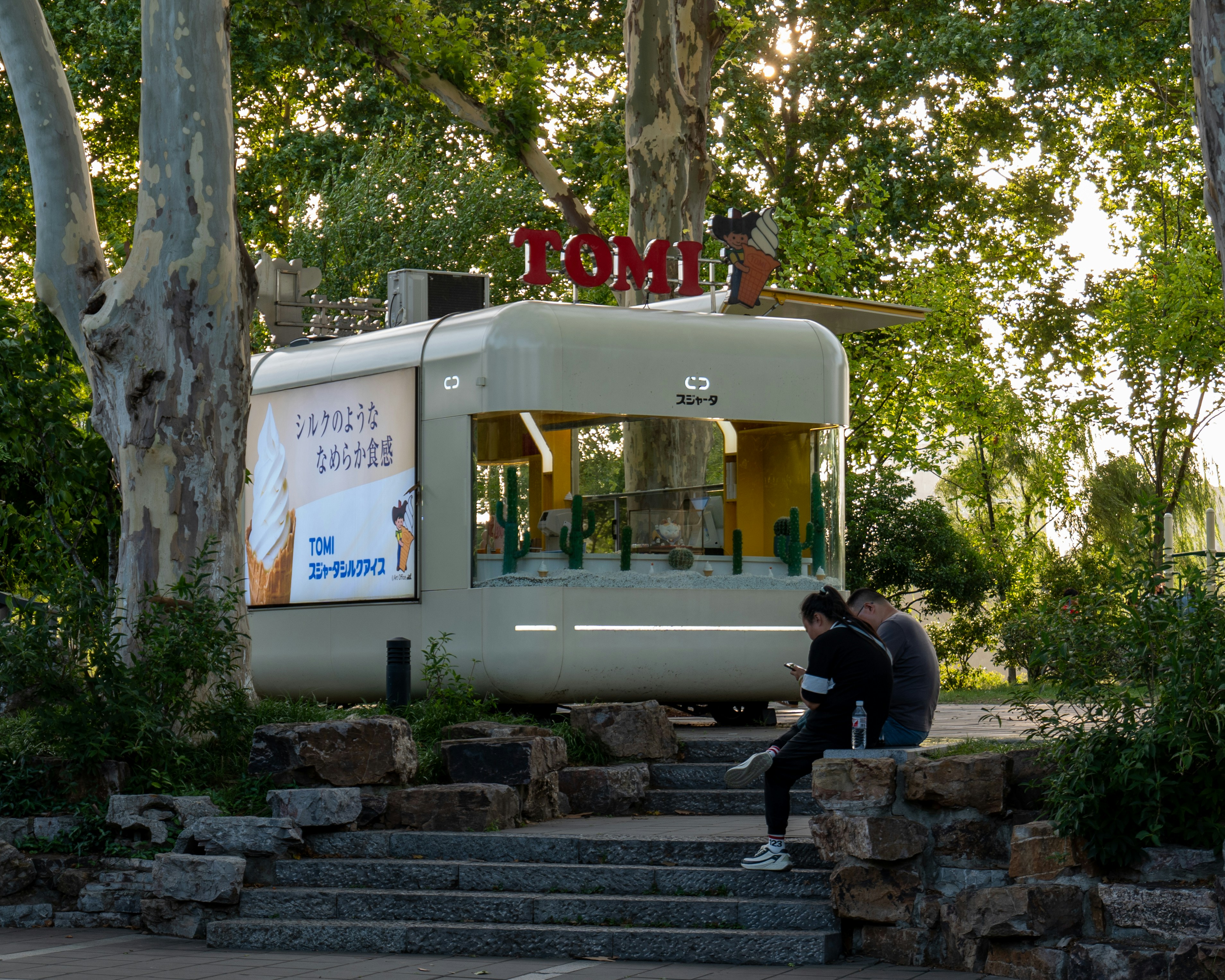 Two men are sitting on the steps outside of a food truck
