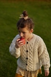 A little girl eating an apple in a field