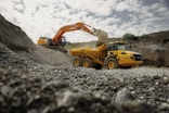 A large yellow truck driving down a dirt road