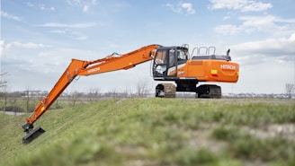 An orange excavator is parked in a field