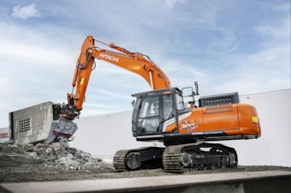 A large orange excavator sitting on top of a pile of dirt