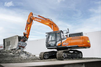 A large orange excavator sitting on top of a pile of dirt