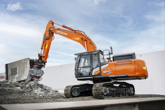 A large orange excavator sitting on top of a pile of dirt