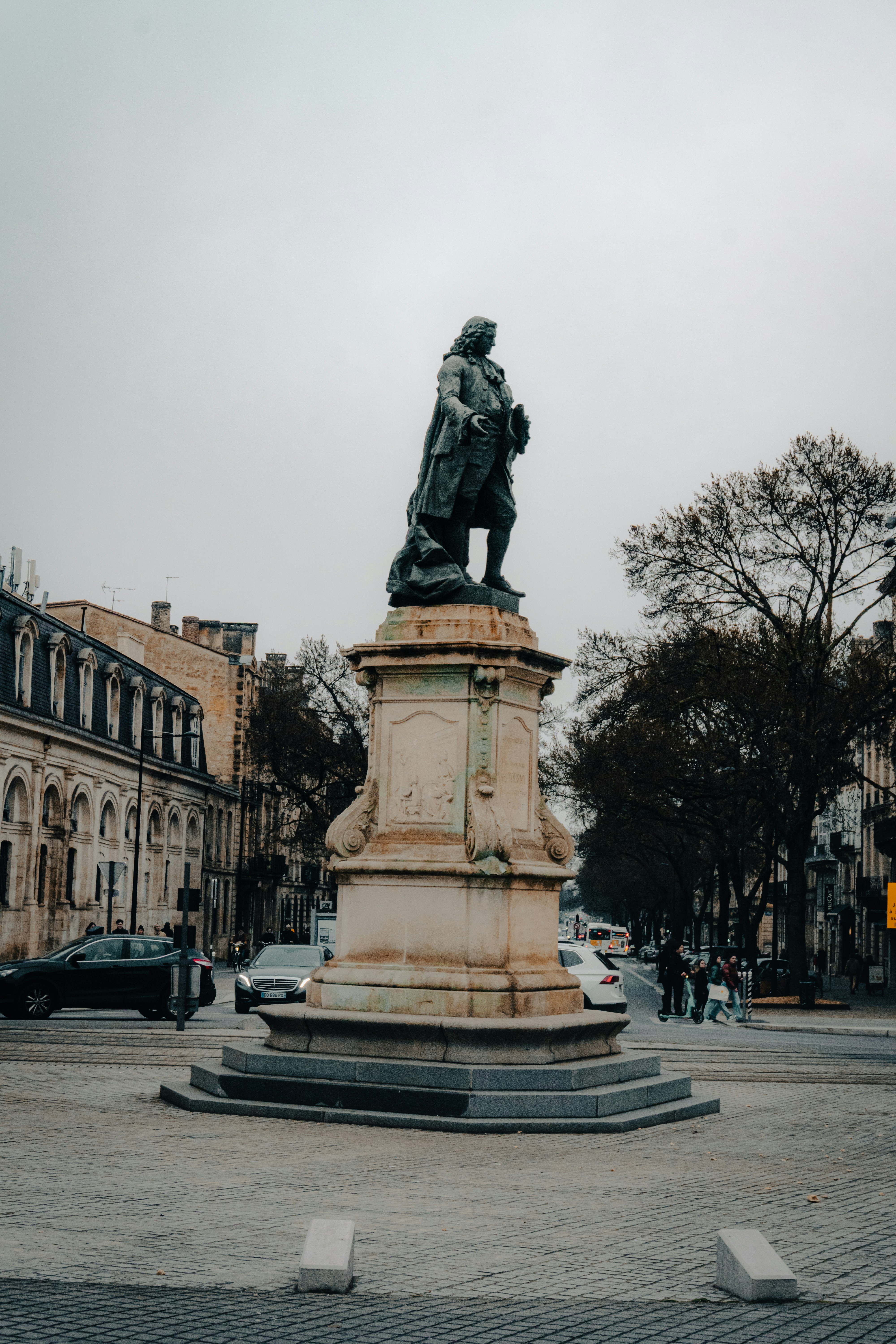 A statue of a man on a pedestal in the middle of a street