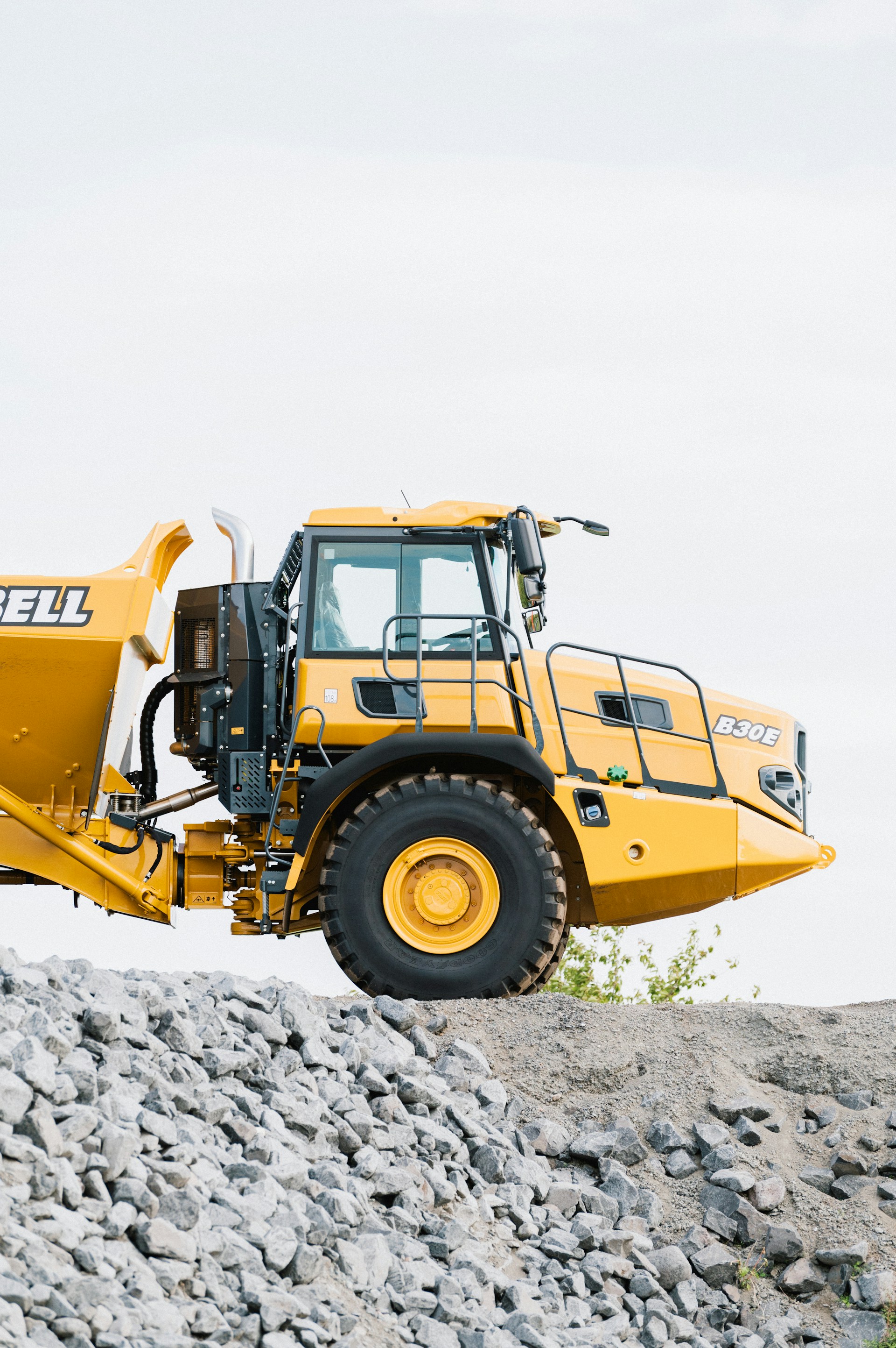 A large yellow dump truck on top of a pile of rocks